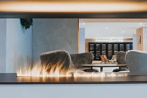 Gemütliche Lounge mit modernem Kamin im Hotel Tauernhof Großarl, eingerahmt von stilvollen Sitzmöbeln und einladender Atmosphäre.
