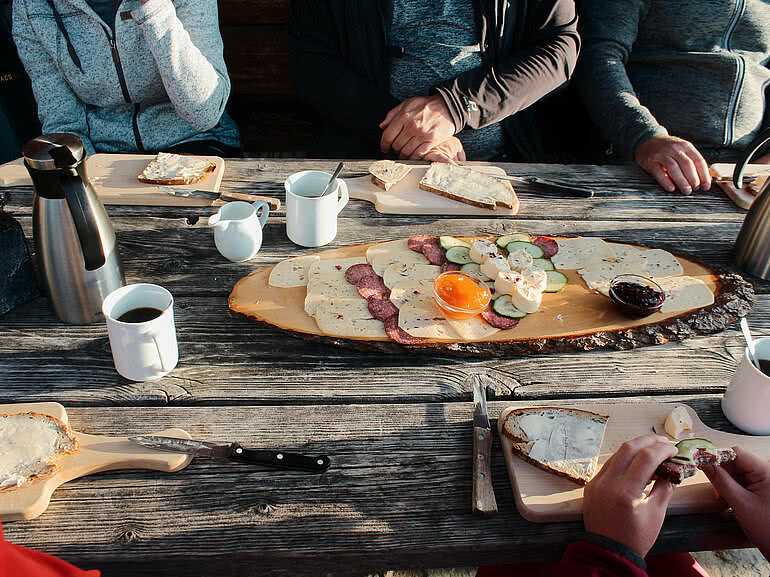 Traditionelle Brettljause mit Käse, Wurst, Brot und Aufstrich auf einem Holztisch nahe Hotel Tauernhof Großarl.