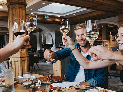 Gruppe stoßen beim Essen mit Wein an