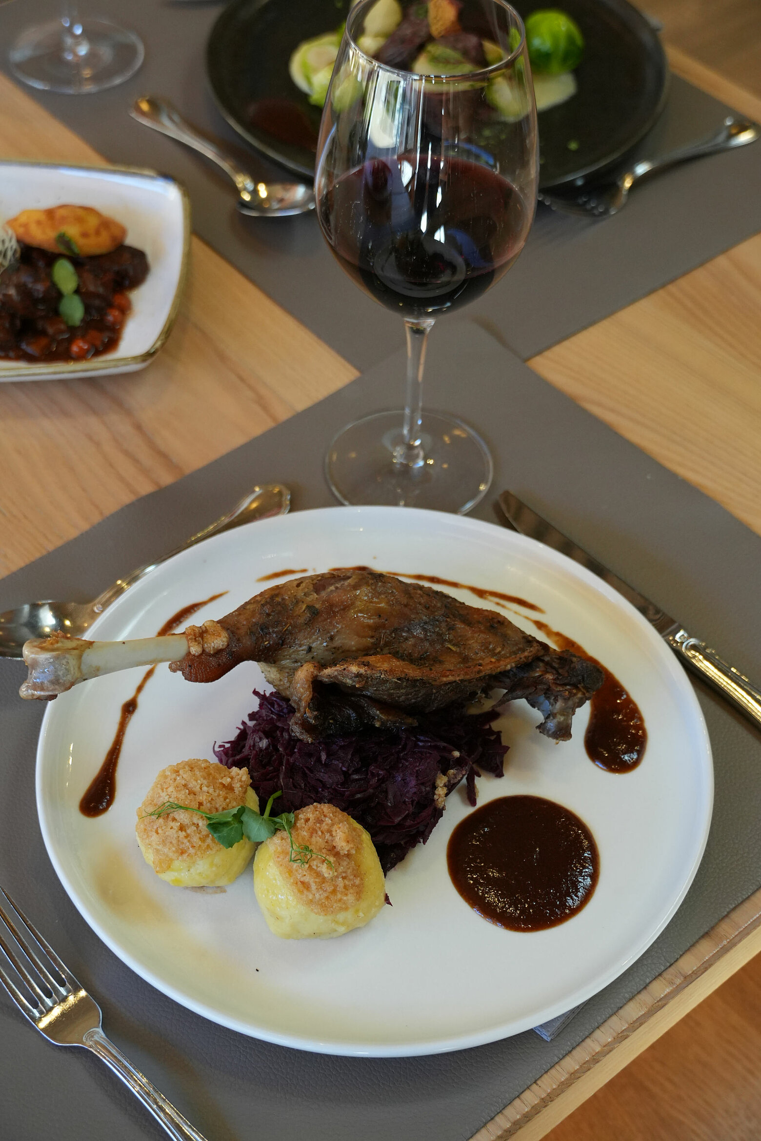 Ein köstliches Gericht mit einer knusprigen Entenkeule auf Rotkohl, serviert mit zwei knusprigen Klößen und einer dunklen Sauce in der Schatzerei des Tauernhofs in Großarl.