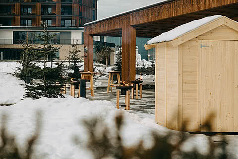 Winterlicher Weihnachtsmarkt am Tauernhof Großarl mit Holzbuden, Feuerstellen und Tannenbäumen im Schnee.