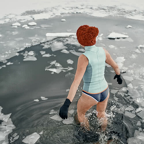 Rear view of an active senior woman in swimsuit outdoors in winter, cold therapy concept.