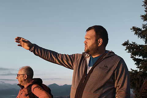 Wanderer betrachten die Umgebung während eines Sonnenaufgangs in den Alpen nahe dem Hotel Tauernhof Großarl, mit klarer Bergluft und beeindruckender Aussicht.