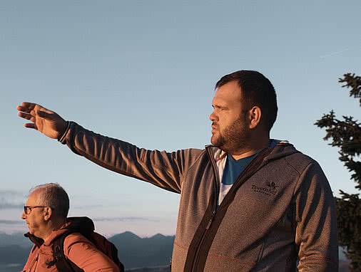 Wanderer betrachten die Umgebung während eines Sonnenaufgangs in den Alpen nahe dem Hotel Tauernhof Großarl, mit klarer Bergluft und beeindruckender Aussicht.