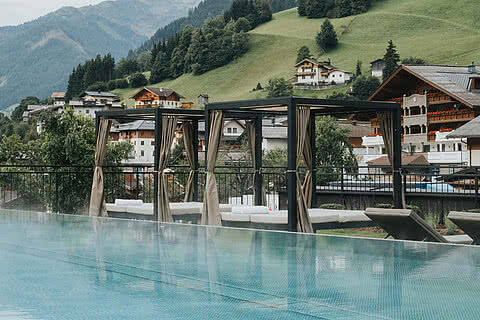 Der Infinity-Pool des Tauernhofs mit Ruheplätzen und Bergblick