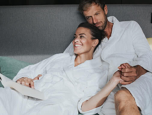 Ein junges Paar in weißen Bademänteln erlebt eine entspannte Zeit im Tauernhof Spa.
