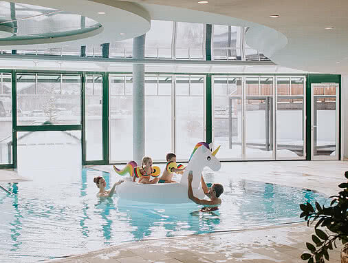 Indoor Familienpool mit Kindern auf Einhorn-Luftmatratze