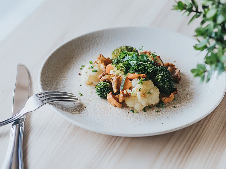 Vegetarisches Gericht mit frischem Brokkoli, Blumenkohl und Pfifferlingen, stilvoll angerichtet im Alpen Retreat Restaurant Schatzarei im Tauernhof Großarl