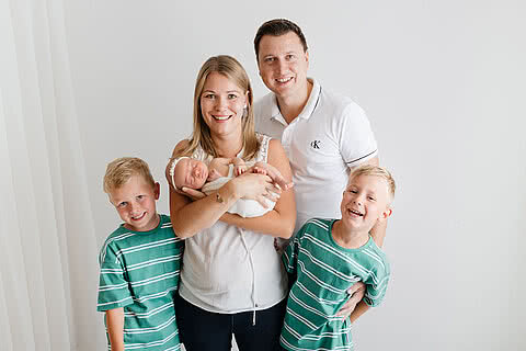 Familienfoto der Familie Hettegger mit Eltern und drei Kindern, liebevoll aufgenommen in freundlicher Atmosphäre des Hotels Tauernhof Großarl.