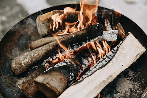 Nahaufnahme einer lodernden Feuerstelle mit brennendem Holz im Außenbereich des Tauernhof Großarl.