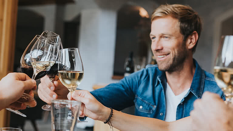 Ski-, Wein- und Genusswoche Gruppe stoßen beim Essen mit Wein an