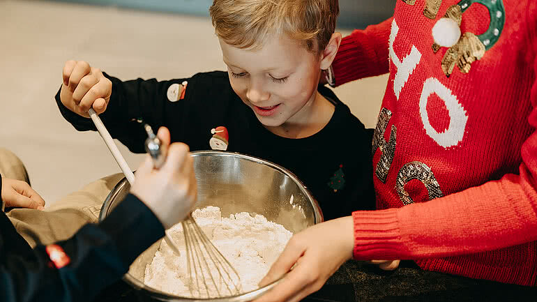 Kinder backen gemeinsam in der Weihnachtszeit und rühren Teig in einer Schüssel im Tauernhof Großarl