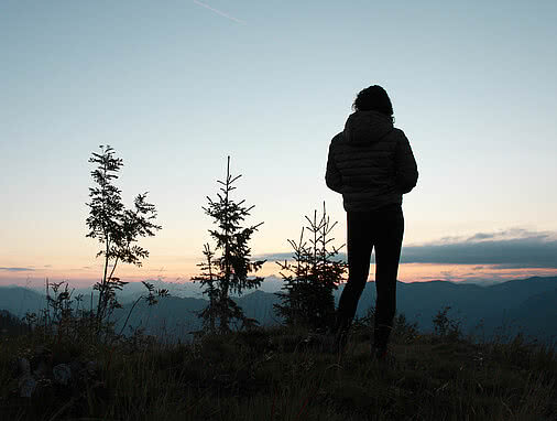 Silhouette einer Person bei Sonnenuntergang nahe Hotel Tauernhof Großarl mit Bergblick.