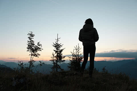 Silhouette einer Person bei Sonnenuntergang nahe Hotel Tauernhof Großarl mit Bergblick.