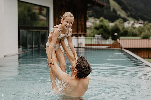 Vater mit Kind genießen Badespaß im Outdoorpool Tauernhof