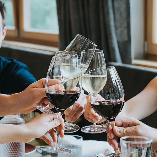 Gruppe stoßen beim Essen mit Wein an