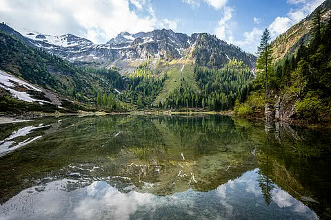Schödersee mit klarer Spiegelung, umgeben von Alpenlandschaft nahe dem Hotel Tauernhof Großarl.