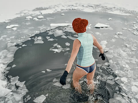Rear view of an active senior woman in swimsuit outdoors in winter, cold therapy concept.