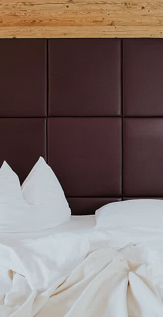 Bed in an Alpine apartment room in the Hotel Tauernhof in Großarl