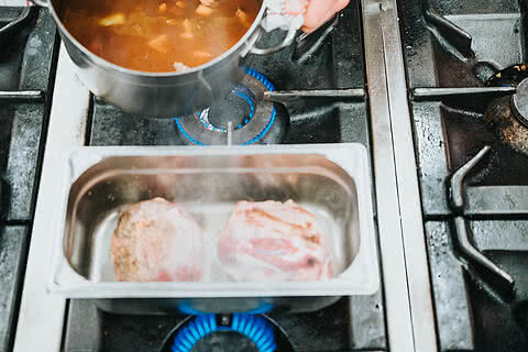 Gemüse-Rotweinsud wird über das Lammfleisch gegeben