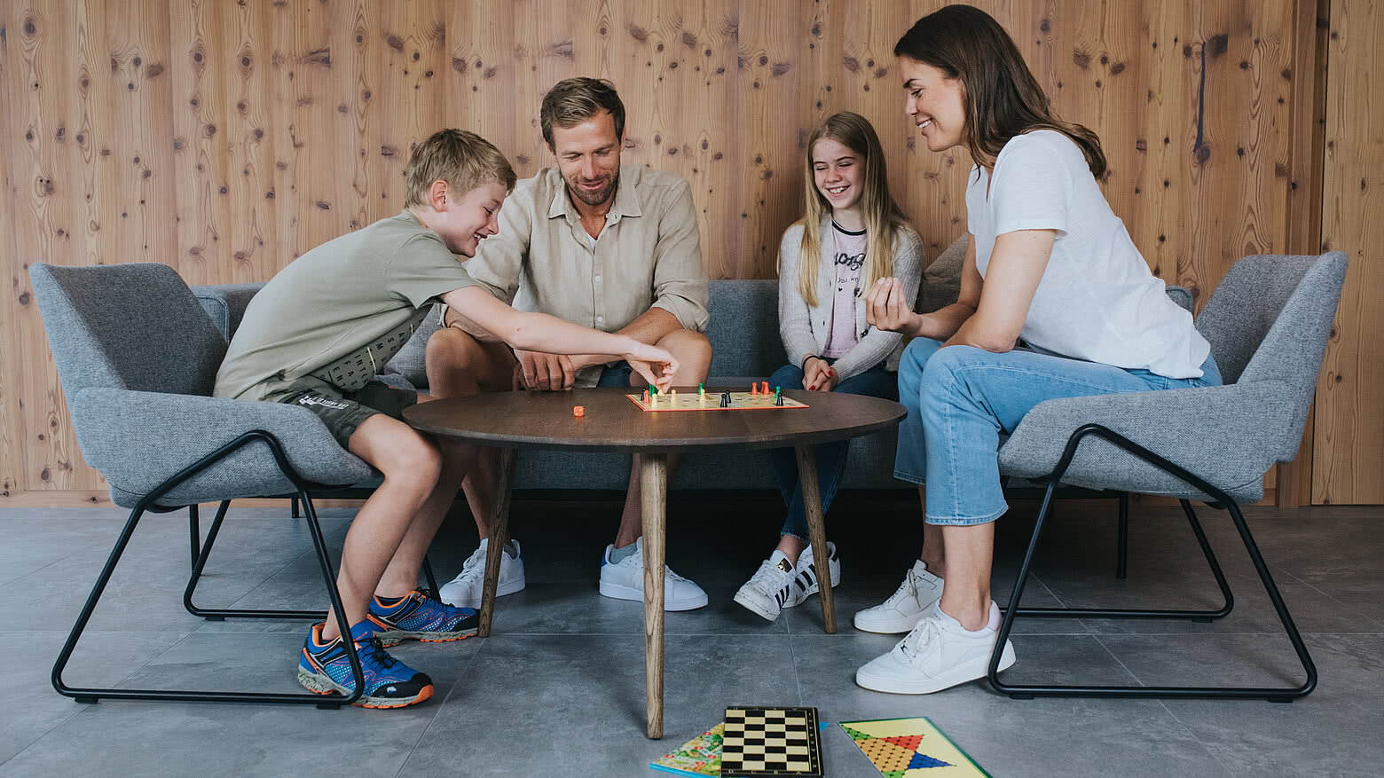 Eine Familie sitzt zusammen an einem Tisch im Hotel Tauernhof in Großarl und spielt ein Gesellschaftsspiel, während sie sichtlich Spaß hat.