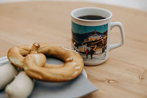 Eine Breze, Weißwurst und eine Tasse Glühwein mit winterlichem Motiv im Tauernhof Großarl.