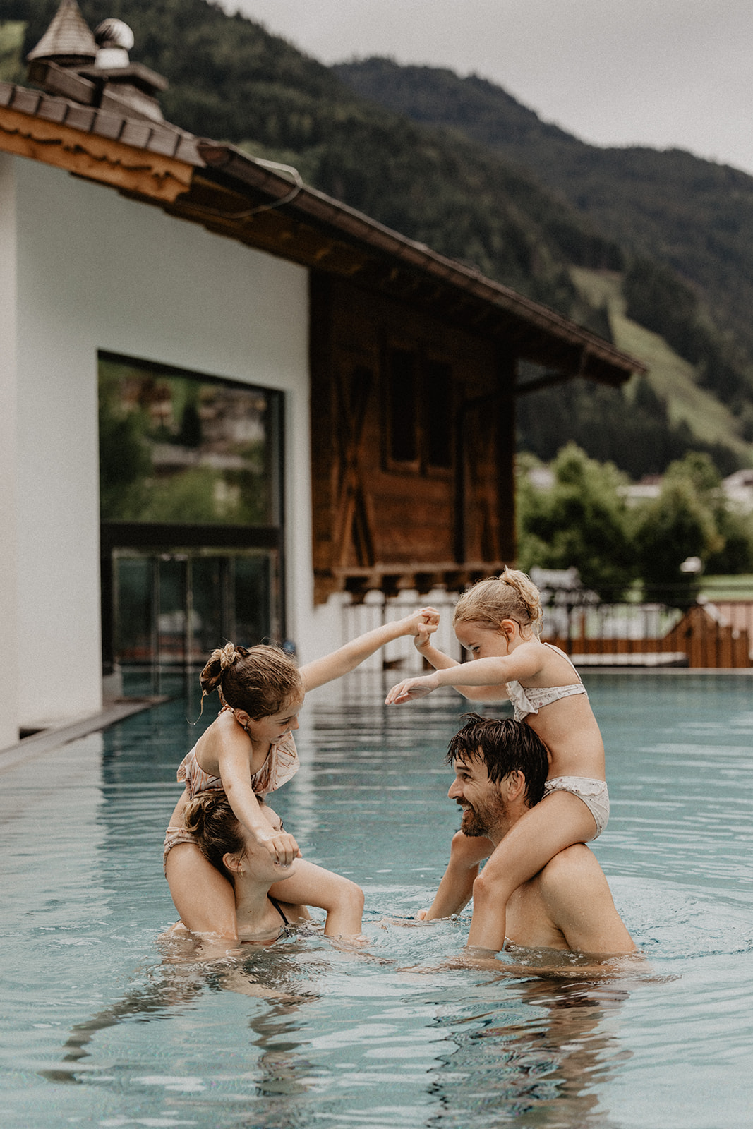 Ein Mann und eine Frau sind in einem Pool, Kinder sitzen auf ihren Schultern